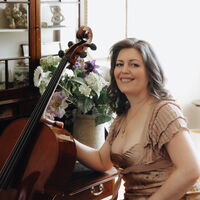Elena Gaponenko lächelnd neben ihrem Violoncello und einem Blumenstrauß